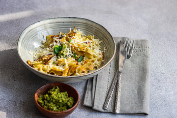 Pesto pasta with cheese and green onion served in the bowl