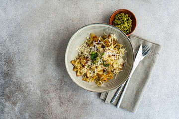 Pesto pasta with cheese and green onion served in the bowl