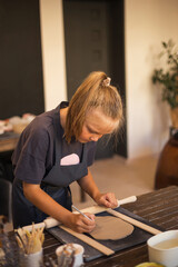 The girl works with ceramic clay in modern pottery workshop. Hob - obrazy, fototapety, plakaty