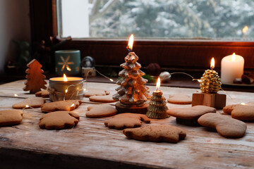 Burning Christmas Tree Candles by a Snowy Window and Gingerbread