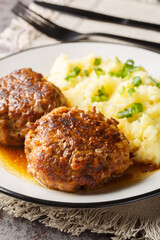Spicy Dutch homemade meatballs with a side dish of mashed potatoes close-up in a plate on the table. Vertical