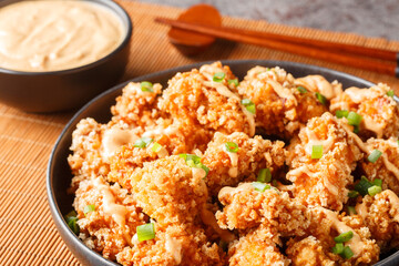 Bang Bang Chicken crispy bites and spicy sauce that will wow your taste buds closeup on the plate on the table. Horizontal