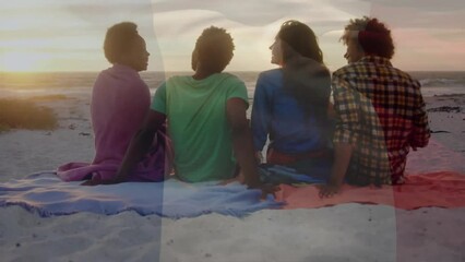 Animation of flag of italy over happy diverse sitting on sunset beach talking - Powered by Adobe