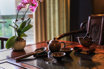 Obraz na płótnie Canvas Tea set on the wooden table in authentic vintage style with orchid flower at the background - dark und moody photography