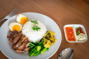 Stewed pork leg with boiled egg and rice on white plate.