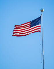waving USA flag on pole against blue sky