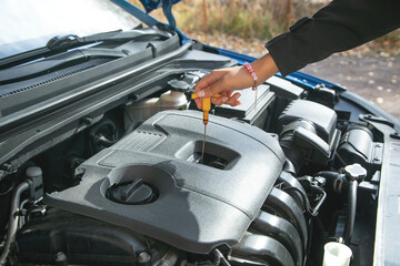 Woman checks the oil level in the car.