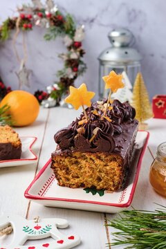 Step-by-step decoration of a carrot cake with chocolate glaze, ganache and candied fruits in a Christmas style on a light wooden background.