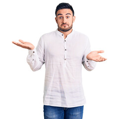 Young handsome man wearing casual clothes clueless and confused expression with arms and hands...