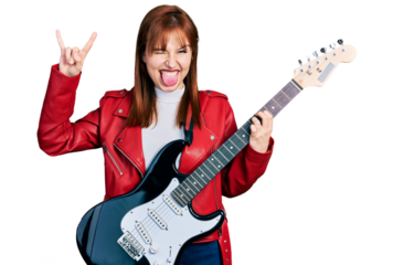 Redhead young woman playing electric guitar doing rock gesture sticking tongue out happy with funny expression.