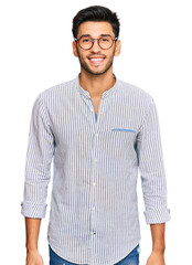 Young handsome man wearing casual clothes and glasses with a happy and cool smile on face. lucky...