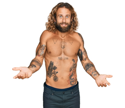 Handsome man with beard and long hair standing shirtless showing tattoos smiling cheerful with open arms as friendly welcome, positive and confident greetings