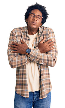 Handsome african american man with afro hair wearing casual clothes and glasses shaking and freezing for winter cold with sad and shock expression on face