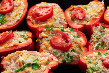 Red peppers stuffed with meat and herbs on a baking sheet before baking in the oven