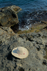 Straw hat on rocks on the seashore