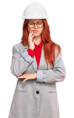 Young redhead woman wearing architect hardhat touching mouth with hand with painful expression because of toothache or dental illness on teeth. dentist