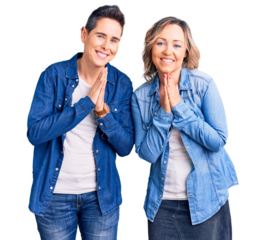 Couple of women wearing casual clothes praying with hands together asking for forgiveness smiling confident.