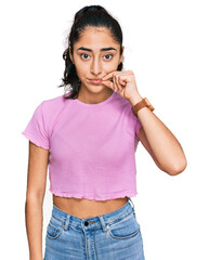 Hispanic teenager girl with dental braces wearing casual clothes mouth and lips shut as zip with...