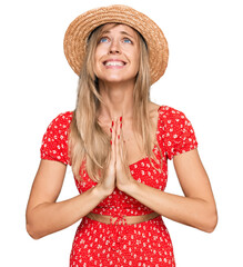 Beautiful caucasian woman wearing summer hat begging and praying with hands together with hope...