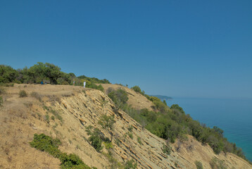 Landscape from a hill cliff with trees and bushes to the blue sea and clear horizon
