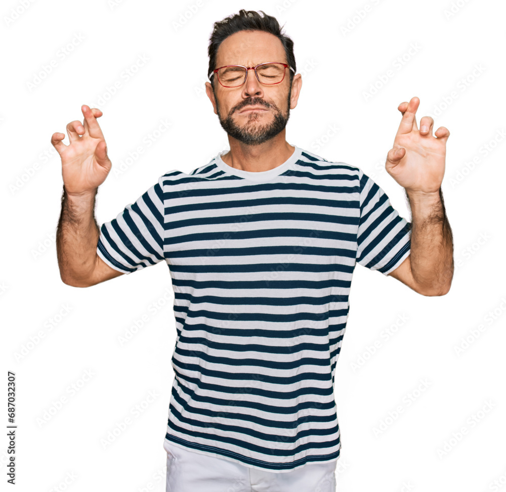 Sticker middle age man wearing casual clothes and glasses gesturing finger crossed smiling with hope and eye