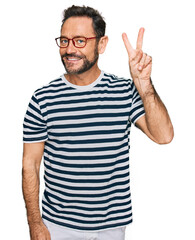 Naklejka premium Middle age man wearing casual clothes and glasses showing and pointing up with fingers number two while smiling confident and happy.