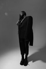 Black and white portrait of young African American woman wearing long dress posing indoor. Vertical.