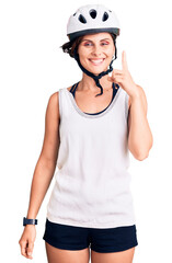 Beautiful young woman with short hair wearing bike helmet pointing finger up with successful idea. exited and happy. number one.