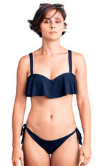 Obraz premium Beautiful young woman with short hair wearing bikini with serious expression on face. simple and natural looking at the camera.