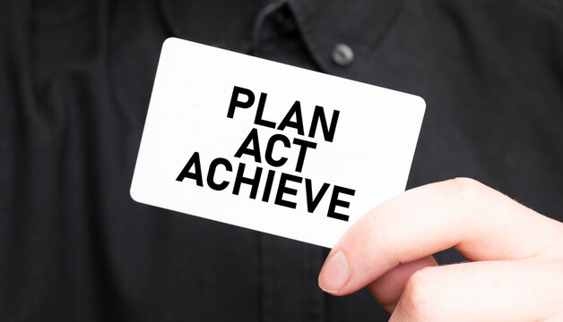 Businessman holding a card with text PLAN ACT ACHIEVE, business concept
