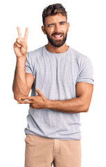 Young hispanic man wearing casual clothes smiling with happy face winking at the camera doing...