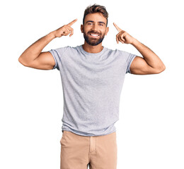 Young hispanic man wearing casual clothes smiling pointing to head with both hands finger, great idea or thought, good memory