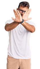 Young hispanic man wearing casual clothes and glasses rejection expression crossing arms doing negative sign, angry face