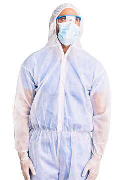 Young hispanic man wearing doctor protection coronavirus uniform and medical mask smiling looking to the side and staring away thinking.