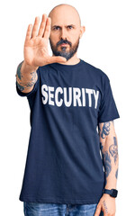 Young handsome man wearing security t shirt doing stop sing with palm of the hand. warning expression with negative and serious gesture on the face.
