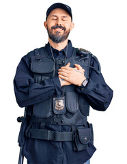 Young handsome man wearing police uniform smiling with hands on chest with closed eyes and grateful...