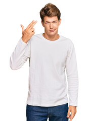 Handsome caucasian man wearing casual white sweater shooting and killing oneself pointing hand and fingers to head like gun, suicide gesture.