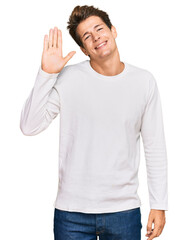 Fototapeta premium Handsome caucasian man wearing casual white sweater waiving saying hello happy and smiling, friendly welcome gesture