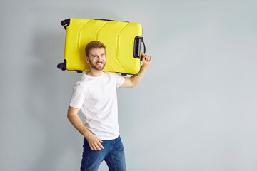 Portrait of a happy young man with a yellow suitcase. Handsome bearded guy in a tee shirt and jeans...