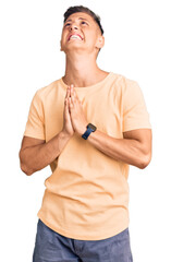 Young handsome man wearing casual clothes begging and praying with hands together with hope...