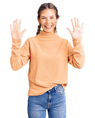 Beautiful caucasian woman with blonde hair wearing casual winter sweater showing and pointing up with fingers number ten while smiling confident and happy.