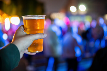 plastic cup glass with beer in hand. Outdoor summer festival