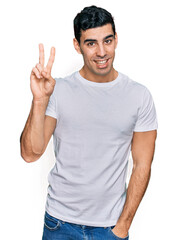 Handsome hispanic man wearing casual white t shirt showing and pointing up with fingers number two while smiling confident and happy.