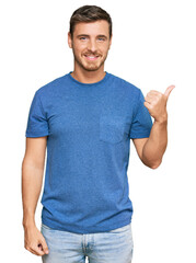 Handsome caucasian man wearing casual clothes smiling with happy face looking and pointing to the side with thumb up.