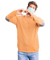 Young handsome man wearing medical mask smiling in love showing heart symbol and shape with hands. romantic concept.