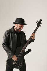 Rock musician. A man with black hat and electric guitar poses at the studio.