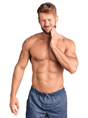Fototapeta premium Young caucasian man standing shirtless touching mouth with hand with painful expression because of toothache or dental illness on teeth. dentist