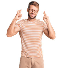 Young caucasian man wearing casual clothes and glasses gesturing finger crossed smiling with hope...
