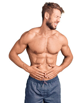 Young caucasian man standing shirtless with hand on stomach because nausea, painful disease feeling unwell. ache concept.