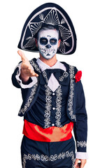 Young man wearing day of the dead costume over background smiling friendly offering handshake as greeting and welcoming. successful business.